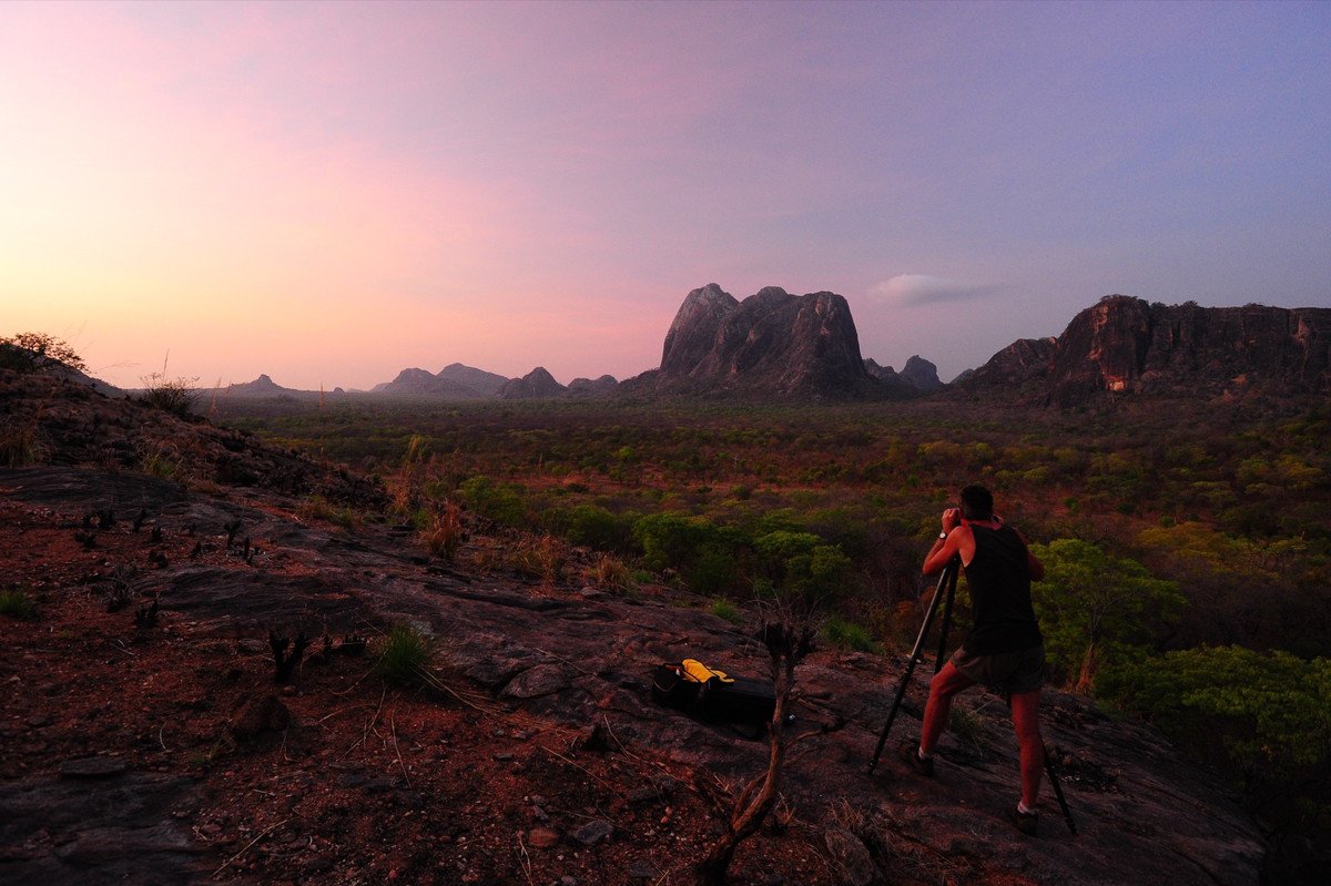 Koos van der Lende at his tripod at dawn, rock domes on the horizon