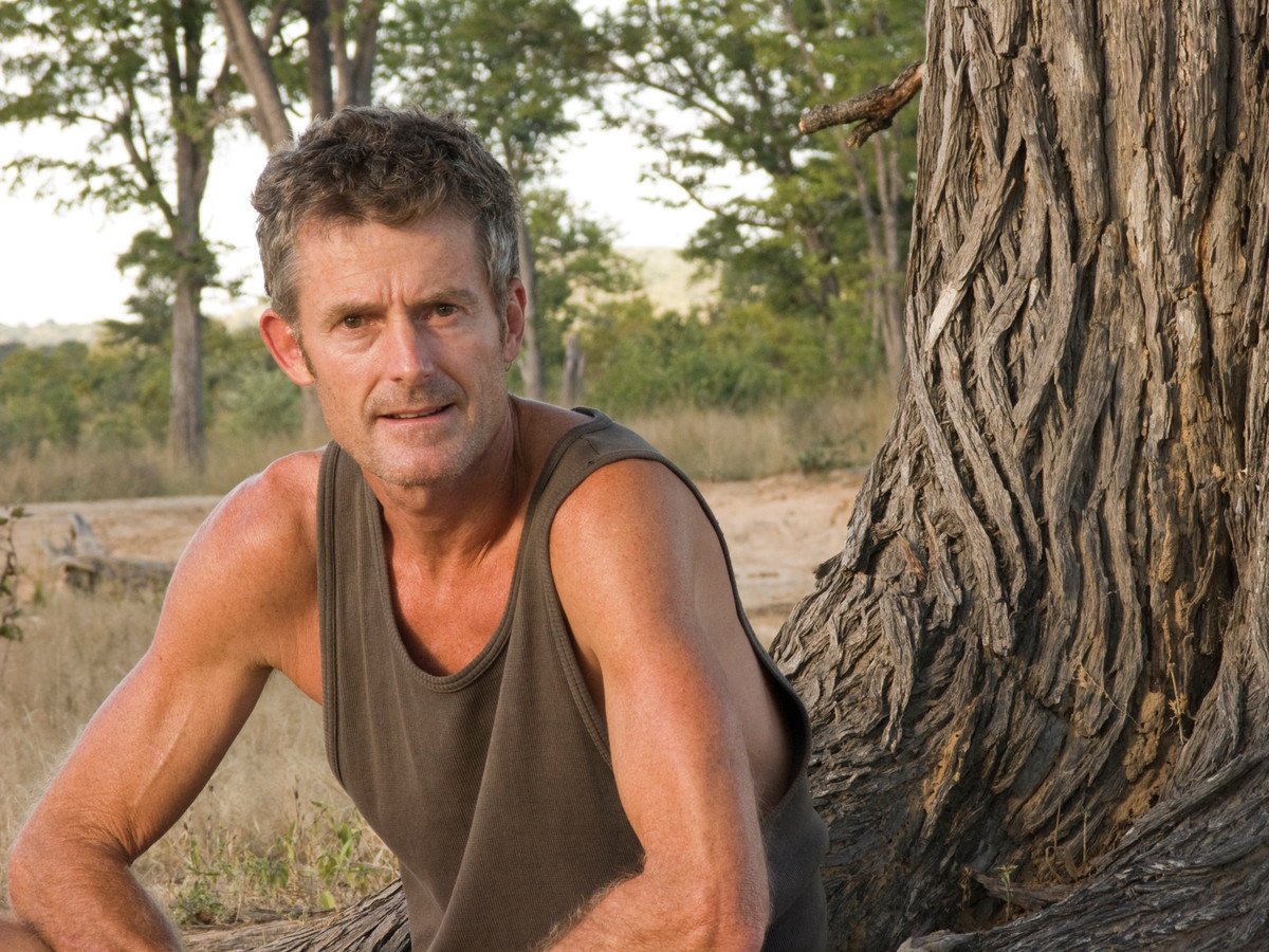 Koos van der Lende resting against the trunk of a great tree in Chizarira